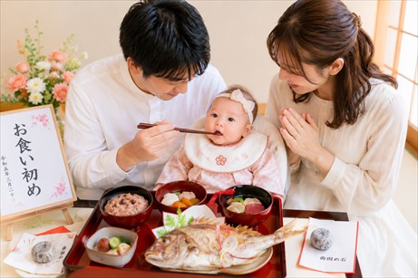 両親が赤ちゃんをだっこして、お食い初め